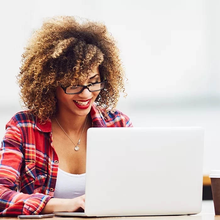 A smiling woman working on a laptop.